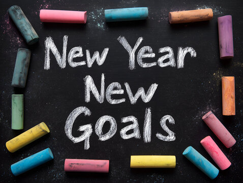 New year new goals written in chalk on a blackboard with colorful chalk sticks