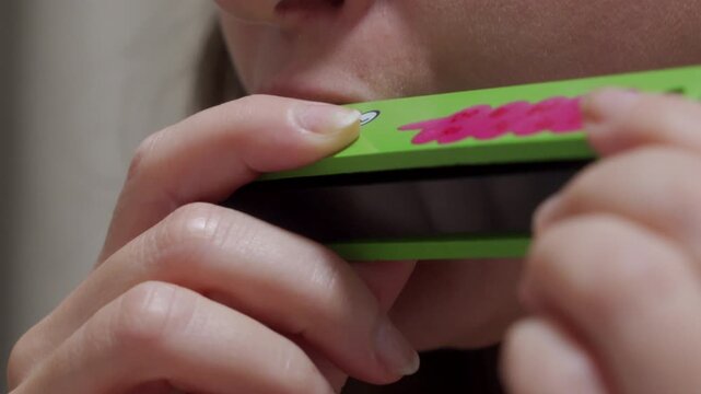 Distinct Note: Hands Hold Wooden Harmonica, Playing a Single Musical Tone.