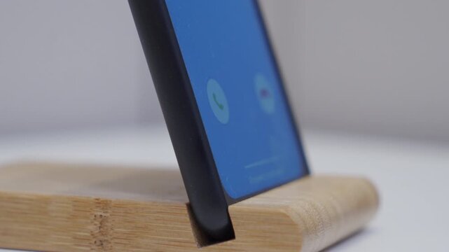 The screen of a phone displays an incoming call notification. The electronic device emits a ringing bell-like melody.