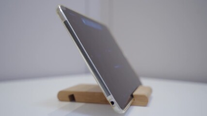 A tablet is resting on a wooden stand. The electronic device plays a church bell timer melody. - Powered by Adobe