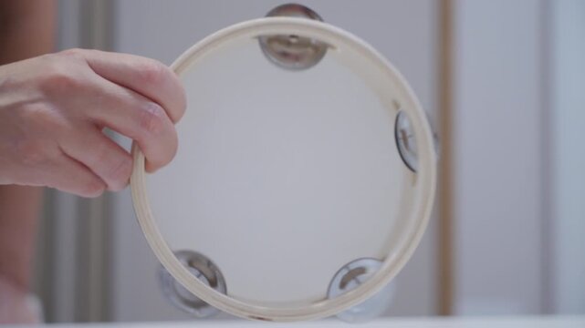 Hand Gently Shakes Headless Wooden Tambourine, Making Subtle Jingle