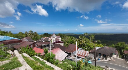 Tranquil Hill Village Surrounded by Lush Green Landscape Under Clear Blue Sky
