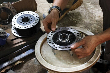 Focused mechanic working motorcycle brake disc workshop. skilled technician shows concentration while assembling custom metal part for vehicle, highlighting industrial repair and precision