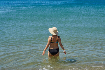 Rear view of a retired woman in a swimsuit getting ready to swim in the sea