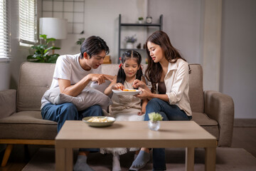Asian family eating, bonding together in living room