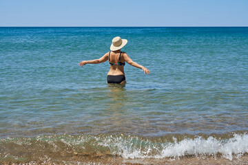 middle-aged woman in a swimsuit , in a hat getting ready to swim in the sea