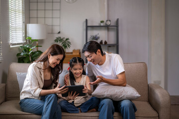 Asian family using digital tablet on sofa at home