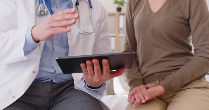 Doctor in white medical uniform using tablet online talking with patient to discuss results, symptoms, GP or physician consulting client, gives recommendation at meeting in hospital clinic, explaining
