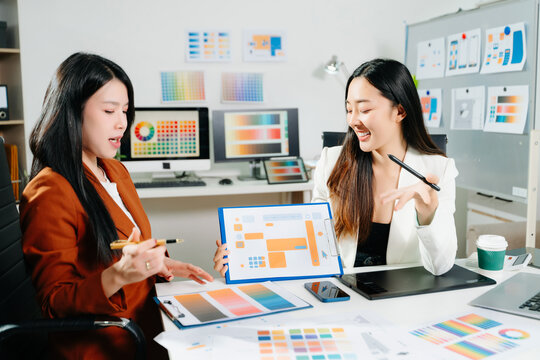 Two professional women designers discussing UX UI and color palette in a creative modern office. Ideal for teamwork, innovation - Powered by Adobe