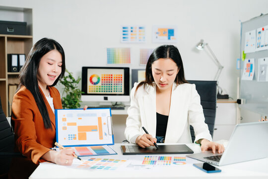 Two professional women designers discussing UX UI and color palette in a creative modern office. Ideal for teamwork, innovation