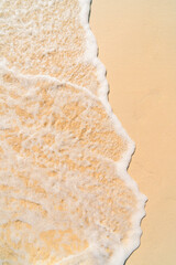 The image shows a close-up of sea foam rolling onto a sandy beach.
The clear dividing line between the foam and the dry sand creates a minimalist and abstract visual effect.