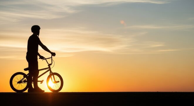 Man biker silhouette with bmx bicycle at sunset. Concept of youth lifestyle, extreme sport, freedom, and adventure. Outdoor activity.