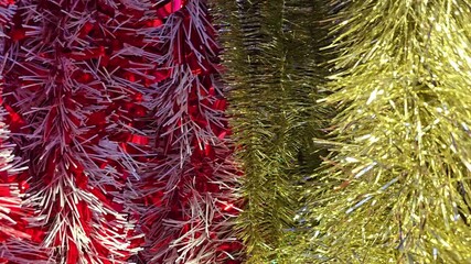 Slow panning shot from left to right showing shiny red, white, and gold Christmas tinsel decorations hanging in a festive display. - Powered by Adobe