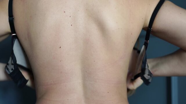 Bra, unfastening, woman unhooking her black lace bra from the back, preparing for an intimate moment