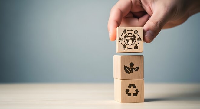 Hand stacking wooden blocks with eco friendly symbols representing sustainability and environmental protection