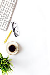 Home office workspace with computer keyboard and cup of coffee on white background, top view. Education online. Tabletop of freelancer.