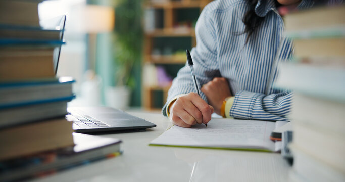 College student, hands or writing notes with pen in book, learning knowledge or exam preparation. Studying, course revision and woman with laptop for academic assessment, test info or subject summary