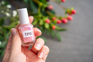 Pink gel nail polish bottle labeled TPO held in hand. Focus on harmful ingredient Trimethylbenzoyl...
