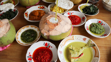 Various menus on white plates from a Padang cuisine restaurant consisting of fish curry, and other dishes like fried small fish with red chilli arranged in neat pile table. Minang or Minangkabau food.