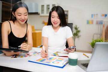 Female fashion designers discussing new clothing collection ideas in studio.