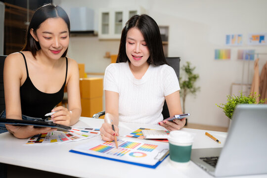 Female fashion designers discussing new clothing collection ideas in studio.