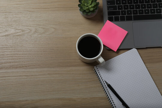 close up photo flat lay laptop keyboard cup of drink sticker folder clips spiral copybook with pen yellow leaves isolated brown background with empty space
