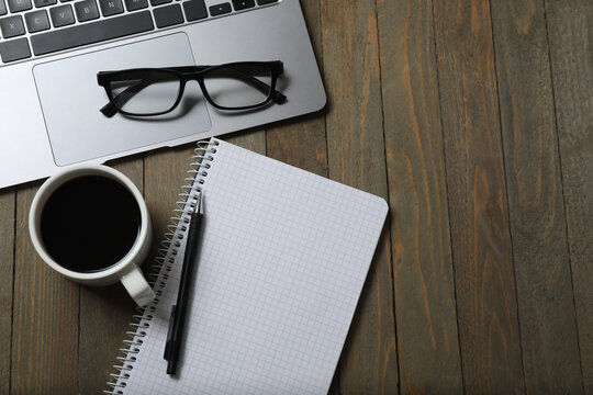 close up photo flat lay laptop keyboard cup of drink sticker folder clips spiral copybook with pen yellow leaves isolated brown background with empty space
