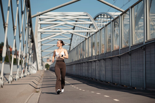 Woman Jogging on Urban Bridge