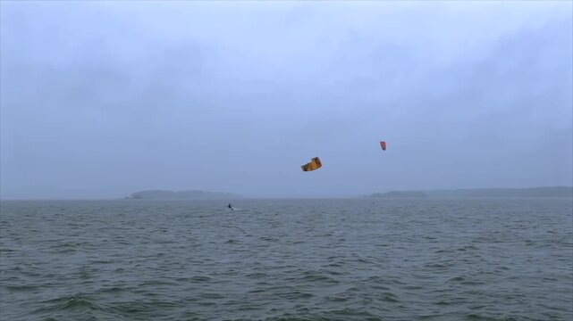 Kitesurfer Jumps Above Wavy Water on Overcast and Rainy Day