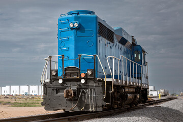 Obraz premium A train engine on tracks leading to industry in background