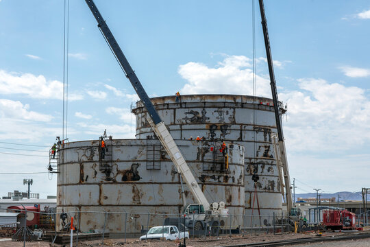 Steel storage tanks being constructed with cranes