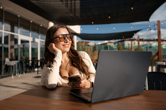 Woman using smartphone and laptop outdoors - Powered by Adobe