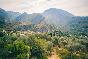 Naklejka premium Summer Landscape with Mountains and View of Village and Olive Grove