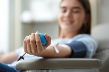 A young woman smiles while donating blood in a comfortable clinic. The atmosphere is calm and supportive, promoting health and community service.
