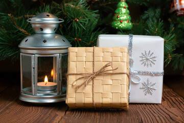 Silver lantern with candle beside wrapped gifts on wooden table, cozy Christmas decor with evergreen. Generative AI