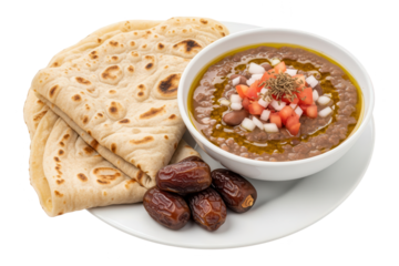 Traditional Indian lentil soup served in a white bowl topped with diced vegetables and spices, accompanied by fresh flatbread and dates on a white