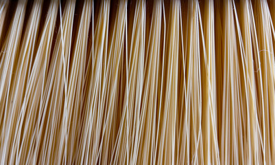 Close-up of household broom bristles made from synthetic beige fibers with vertical pattern, perfect for background, cleaning concept, or domestic product texture.