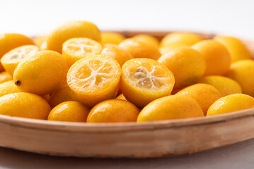 Fresh kumquat fruit in basket on white background