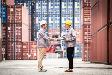 Two men shake hands in front of a large container. Scene is professional and friendly