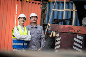 Two men in safety gear stand next to a large red container. They are smiling and seem to be proud of their work