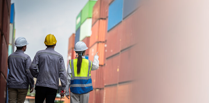 Three people wearing hard hats and safety vests walk down a hallway. They are likely construction workers or engineers - Powered by Adobe
