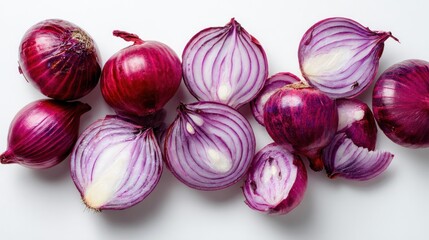 An arrangement of whole and halved red onions, some sliced, on a clean white surface, lit from above