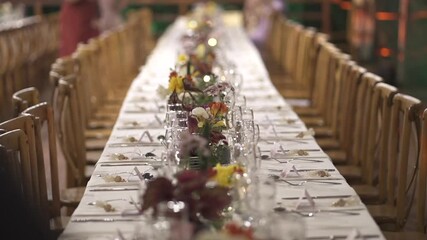 Elegant long dinner table set with candles and flowers prepared for wedding celebration.