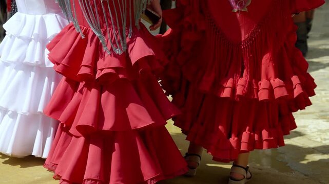 Group of friends in matching flamenco dresses sharing laughs at the Seville fair