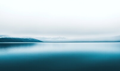 Fototapeta premium A serene landscape featuring a calm body of water reflecting the overcast sky and distant mountains.