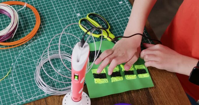 Boy uses scissors to shape plastic details made with 3d pen at workplace closeup. Junior schoolboy works on kids toy parts at design class in school. Technology lesson