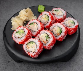 California roll in red tobiko crust. Bright uramaki with crab and cucumber wears vivid roe, styled neatly on black stone.