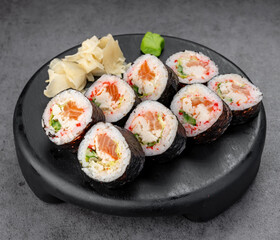 Nori sushi rolls on black plate. Salmon and crab rolls wrapped in nori served neatly on a dark plate