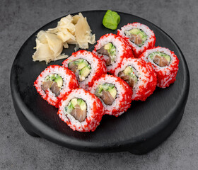 Red tobiko sushi rolls. Bright red tobiko rolls with salmon and avocado arranged on black plate