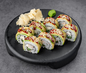 Avocado sushi rolls with eel. Eel and avocado rolls topped with sesame served on a dark plate